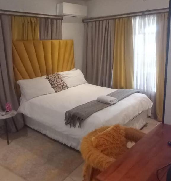 a bedroom with a large white bed and a window at Lifegate Guesthouse in Johannesburg
