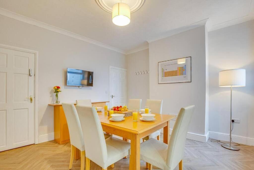 a dining room with a wooden table and white chairs at Manor Castle View 3BR House Free Parking & Garden in Victoria