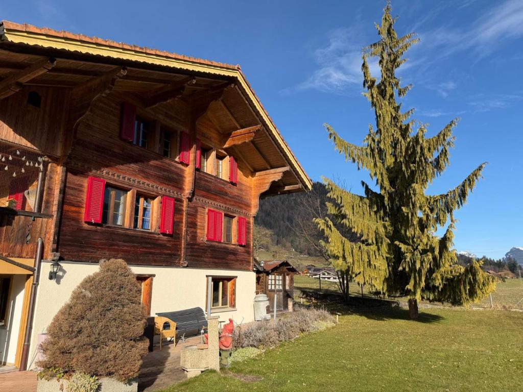 ein großes Holzhaus mit roten Fenstern und einem Baum in der Unterkunft LaVida Peak Mountain Retreat in Frutigen in Wengi bei Frutigen