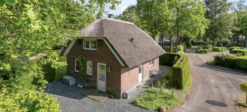a small red brick house with a thatched roof at Boshuis 40 in Epe