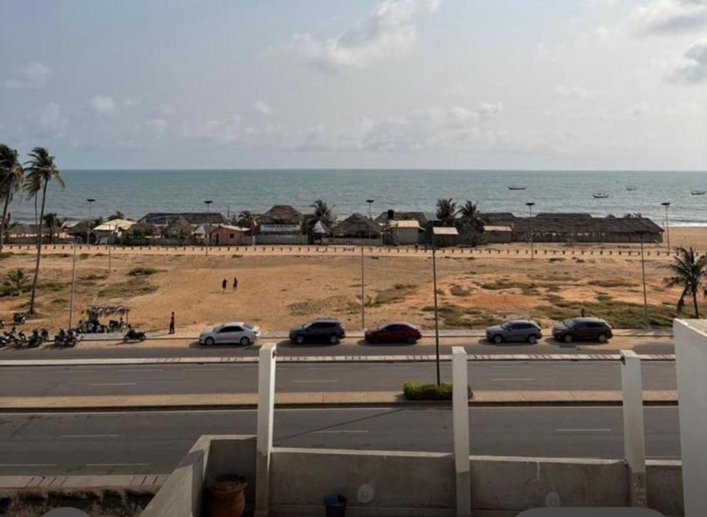 een uitzicht op een weg met auto's geparkeerd op het strand bij Villa Soleil, Face a la Mer C1 in Cotonou