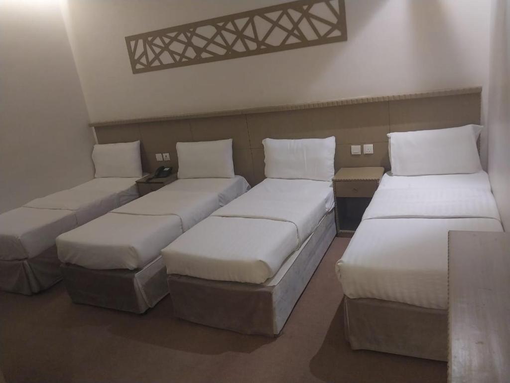 Cette chambre comprend 3 lits avec des oreillers blancs. dans l'établissement فندق الرسالةالذهبي شارع ام القري, à Aş Şafā