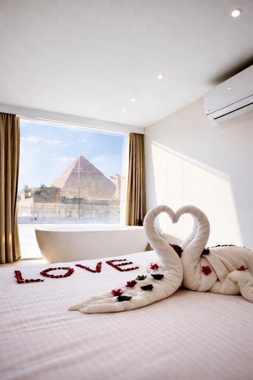 two swans are laying on a bed with heart decorations at LE Grand Pyramids View & Suites in Cairo