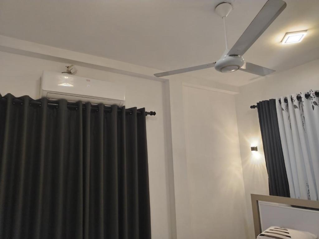 een slaapkamer met een zwart gordijn en een plafondventilator bij Green Haven Villa in Hikkaduwa