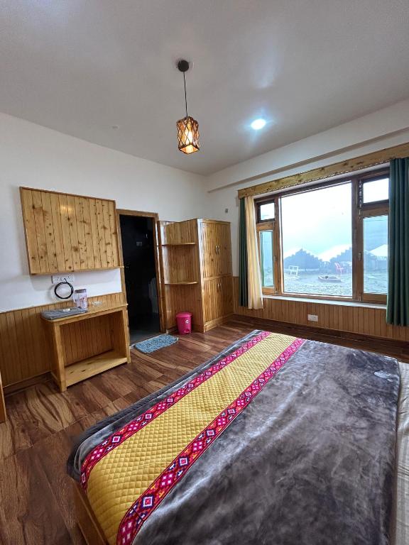 a bedroom with a large bed with a large window at Parashar lake Fogg hill Resort in Prashar lake