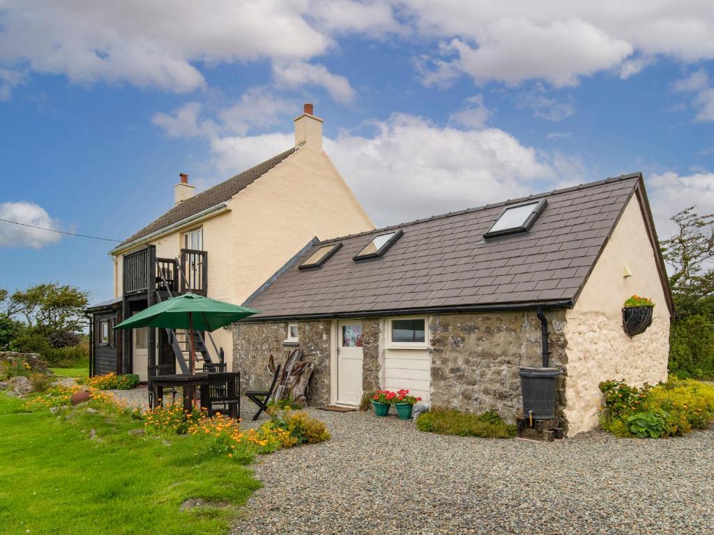 a stone house with a green umbrella in front of it at Rogeston Mount - Cottage in Nolton