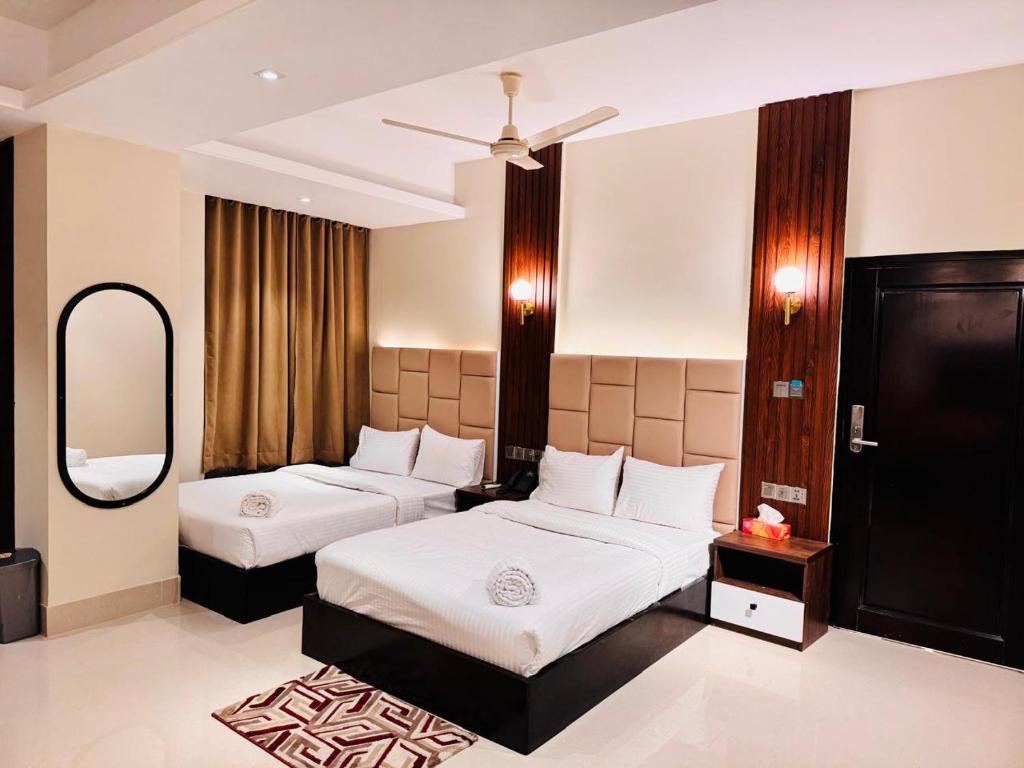 ein Hotelzimmer mit zwei Betten und einem Spiegel in der Unterkunft Grand Khalifa Hotel Hamama in Sylhet