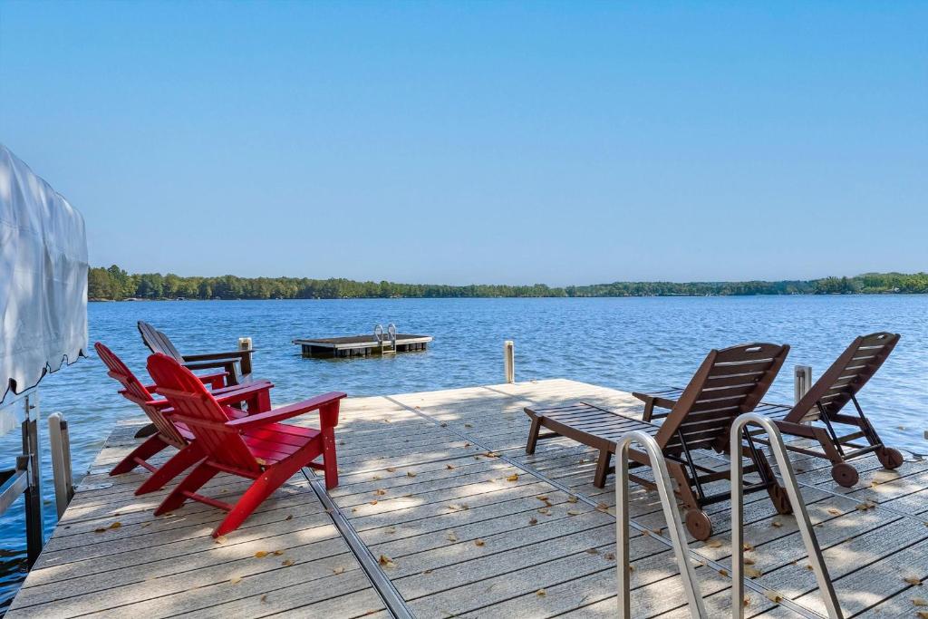 een steiger met vier stoelen en een boot op het water bij Tall Pines Lodge in Eagle River WI in Eagle River