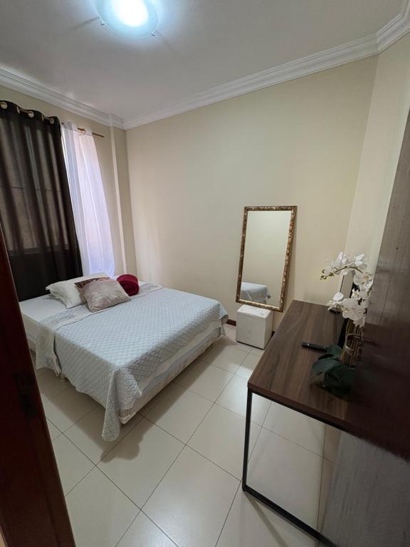 a bedroom with a bed and a mirror and a table at Quarto em apartamento in Ouro Preto