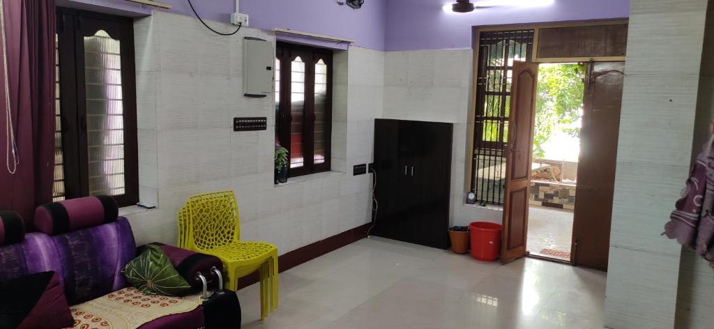 ein Wartezimmer mit einem gelben Stuhl und einer Tür in der Unterkunft Block White Town Home Stay in Puducherry