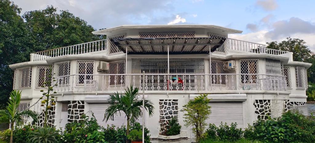 ein weißes Haus mit einem Balkon darauf in der Unterkunft Chavan White House Farm and Stay in Badlapur
