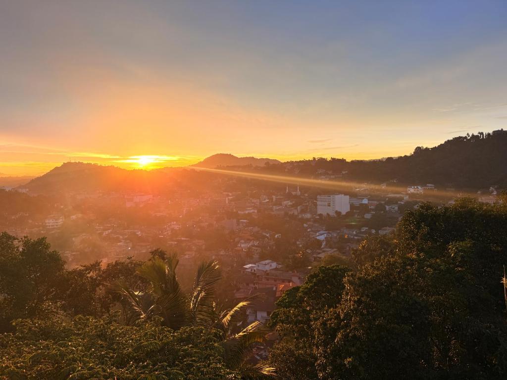 a sunset view of a city with the sun setting at Hanthana Heights in Kandy