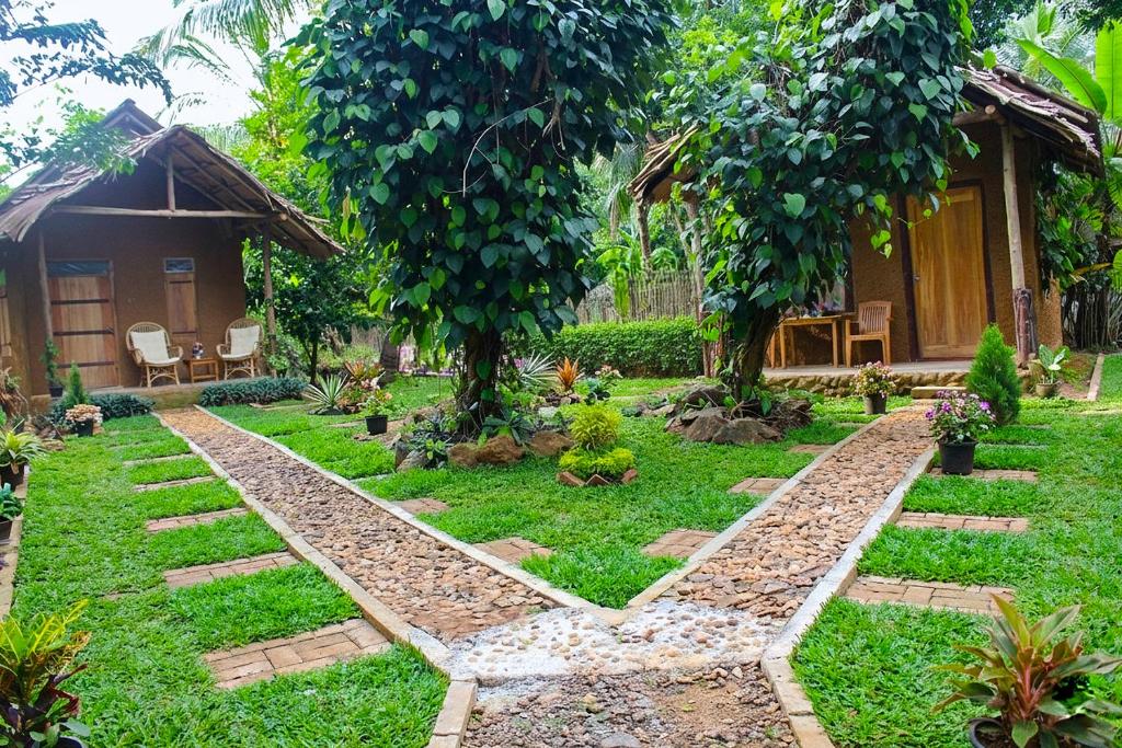 een tuin voor een huis met twee bomen bij Almond Breeze Cottage in Udawalawe