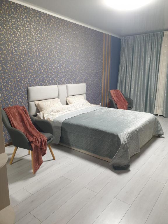 a bedroom with a bed and two chairs at Видові апартаменти на пляжі in Cherkasy