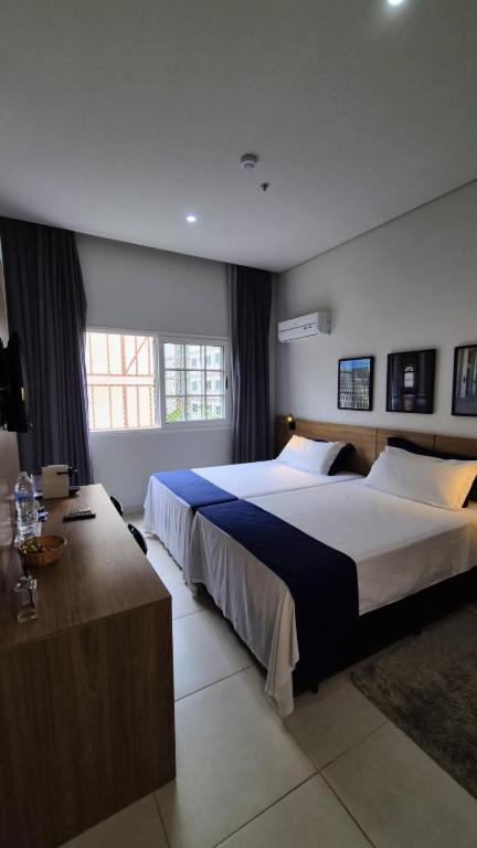 a hotel room with two beds and a desk at Granja Brasil puc 10 2 in Petrópolis