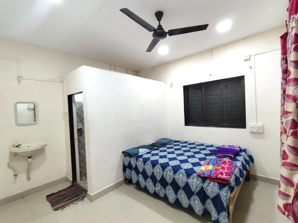 een slaapkamer met een bed, een wastafel en een plafondventilator bij Chaitanya Beach Reesort in Dapoli