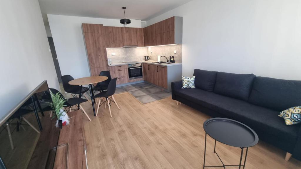 ein Wohnzimmer mit Sofa, Tisch und Stühlen in der Unterkunft Sadyba Apartament in Nowy Sącz