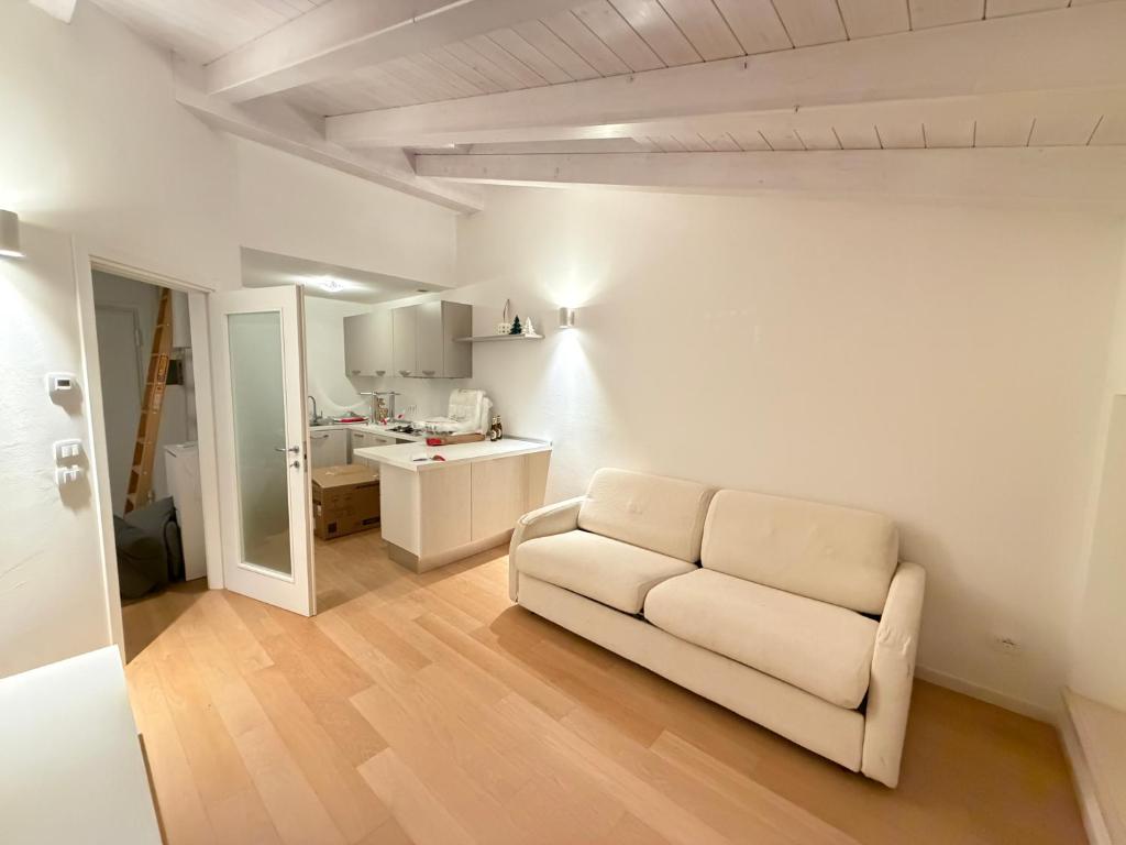 a living room with a white couch and a kitchen at La Piccola Perla di Rovereto in Rovereto