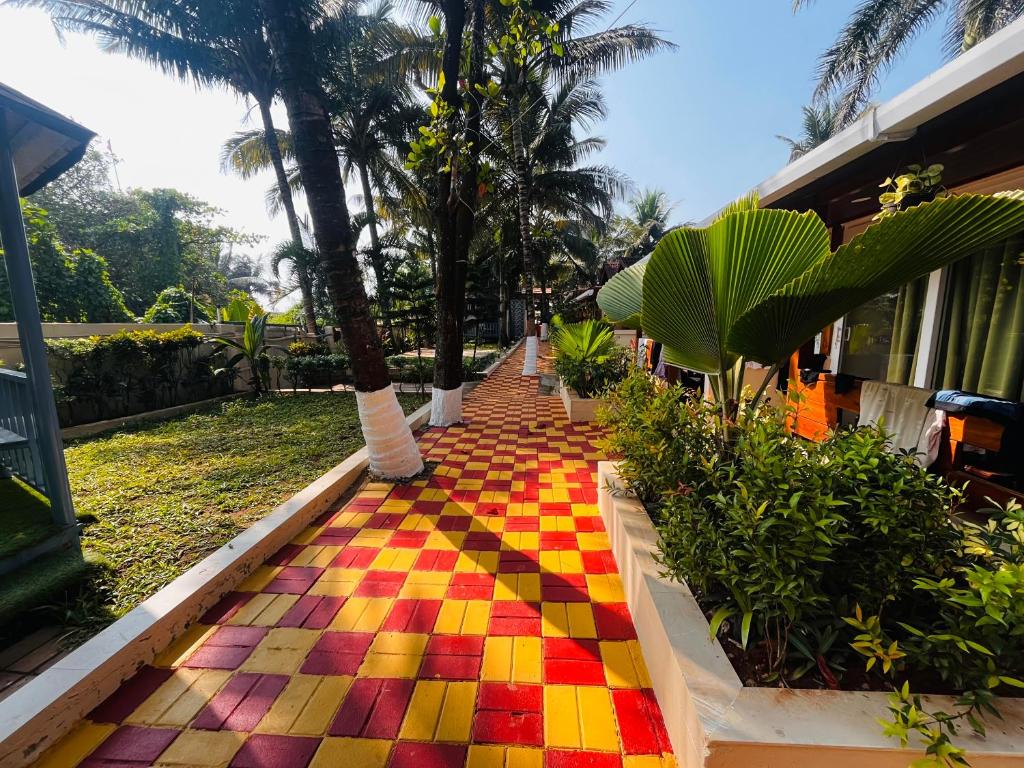 a colorful tiled walkway with palm trees and a building at Maitree Beach Resort in Arambol