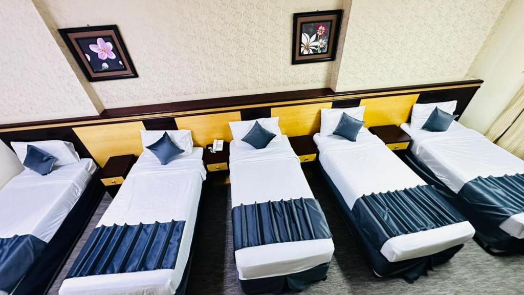 een rij bedden in een kamer met schilderijen aan de muur bij فندق درة السليمانية in Quai