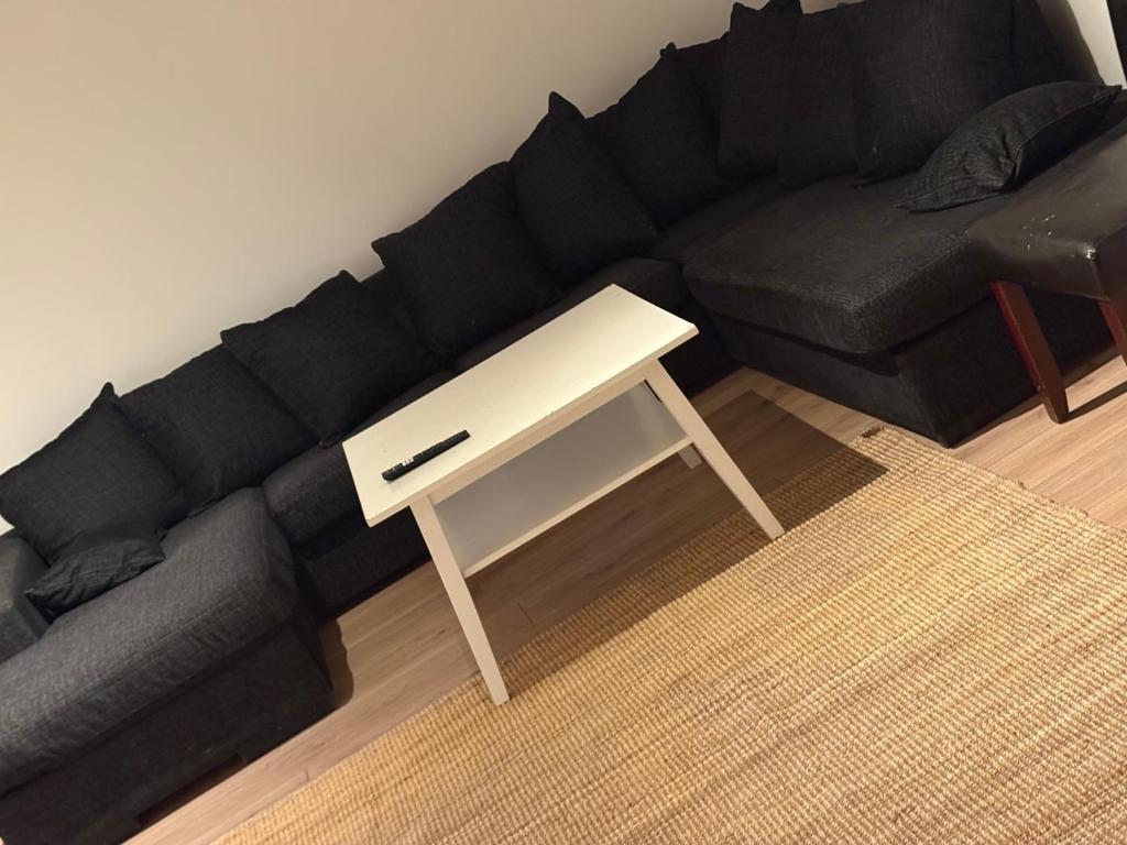 uma sala de estar com um sofá preto e uma mesa branca em High Coast Stay em Ramvik