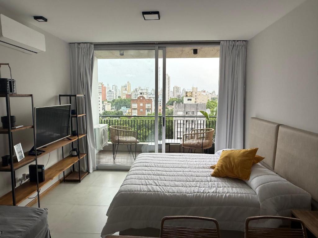 une chambre avec un lit et une grande fenêtre dans l'établissement Departamento Estudio Deluxe, à La Plata