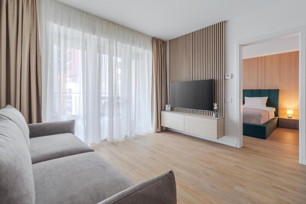 a living room with a couch and a bed and a television at Velour Suites in Oradea