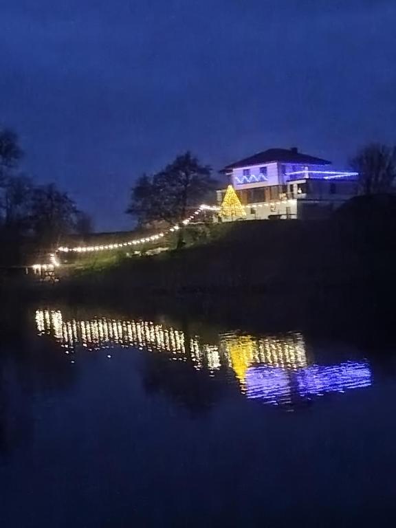 a night view of a house with lights in the water at Malownicze Owieczki in Owieczki