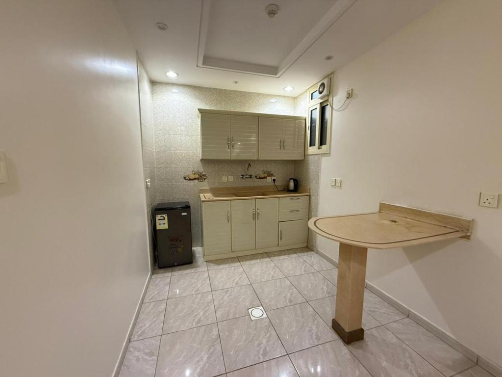 een keuken met een houten tafel in een kamer bij فيو المنسك للشقق المخدومه in Abha