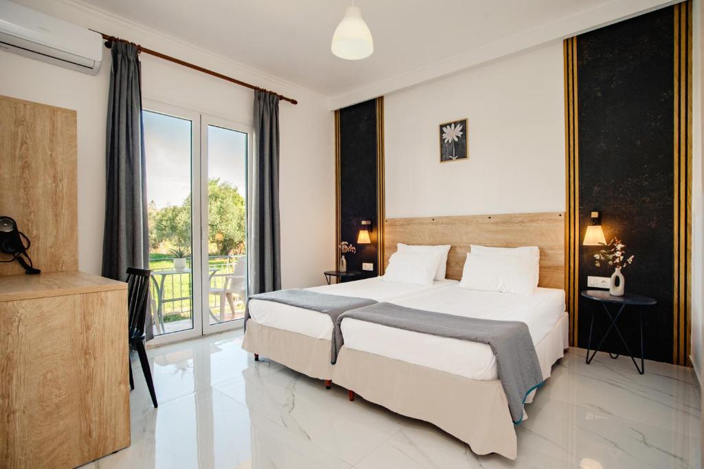 a bedroom with a large bed and a balcony at Kokkinia Gardens in Kavos