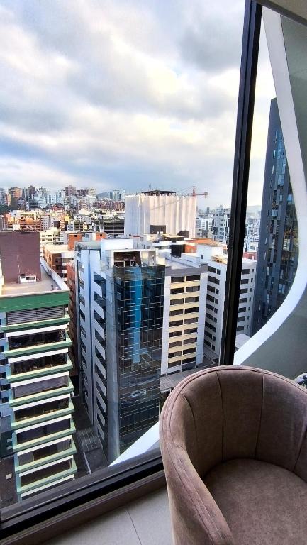 a view of a city from a window with a chair at Harmony Skyline Suite14th Floor View & Luxury Spa in Quito