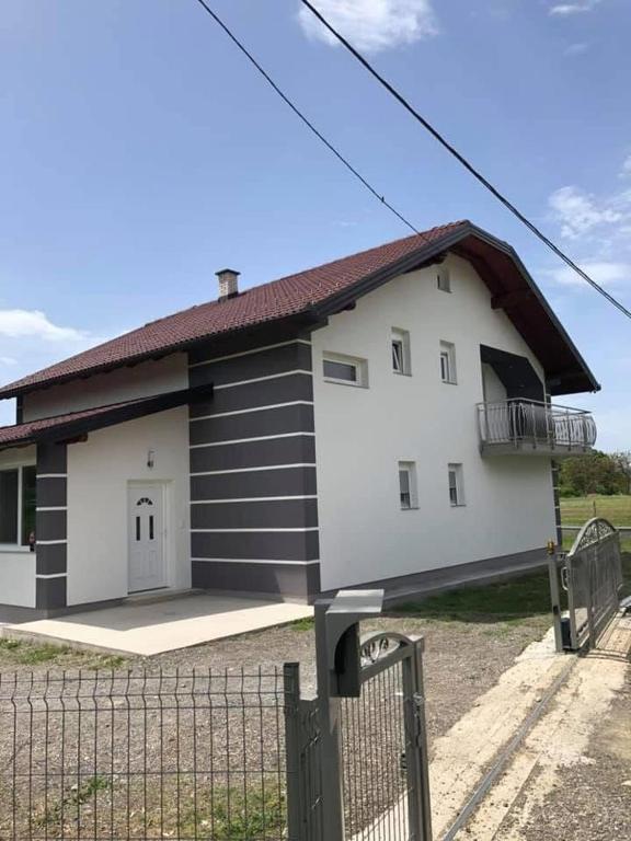 a large white and black building with a fence at Sobe DANA Banja Vrućica in Teslić