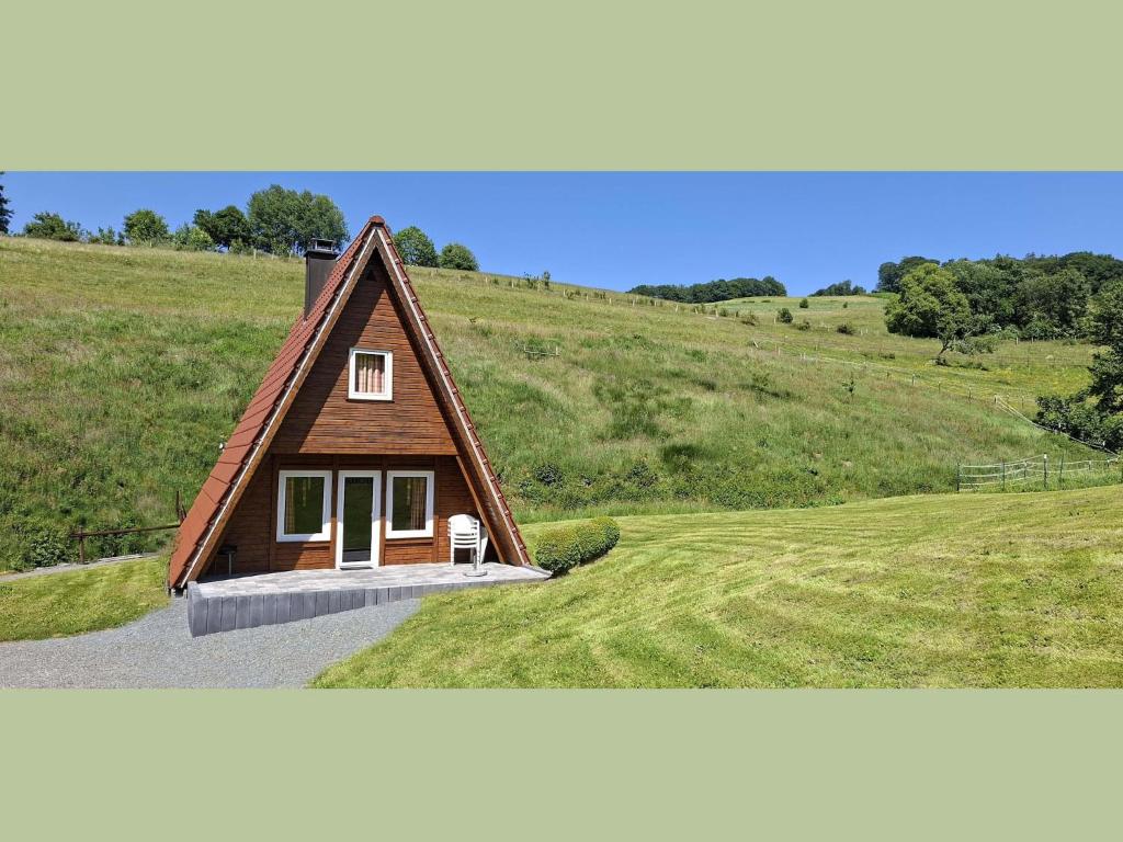 a small house on top of a grassy hill at Charmantes Ferienhaus in Skigebietsnaehe in Schmallenberg