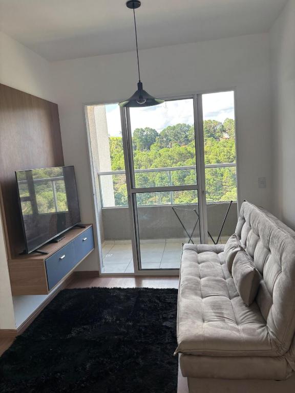a living room with a couch and a flat screen tv at Blue da Mantiqueira in Extrema