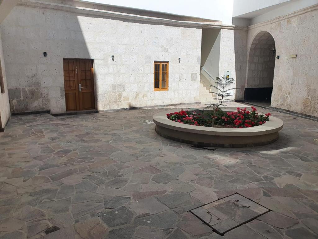 Ein großer Raum mit einem Innenhof, in dem ein Pflanzkübel mit roten Blumen steht. in der Unterkunft Departamento Centrico Yanahuara Beaterio in Arequipa