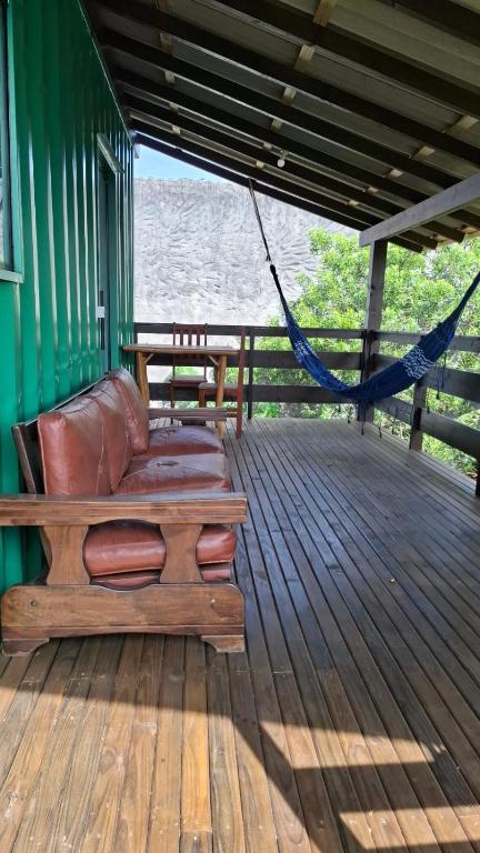 a bench sitting on a deck with a hammock at Recanto dos Pássaros in Palhoça