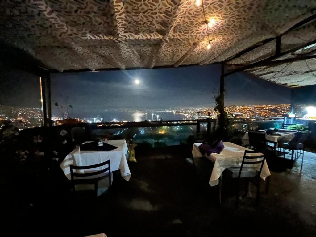 a restaurant with tables and a view of a city at Apart Hotel Jagui Haus Departamentos tipo Loft y Hermosa Terraza con vista al Mar in Valparaíso