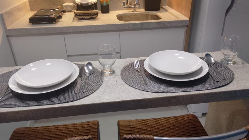 a table with white plates and silverware on a counter at Apartamento 2 quartos Mamelucos in Salvador