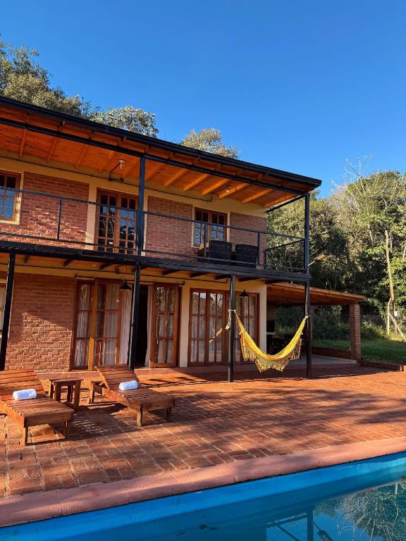 a house with a hammock on a patio next to the water at Amambay in Puerto Bossetti