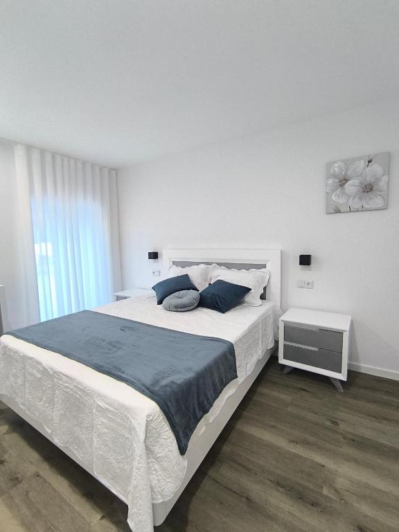 a white bedroom with a large bed with blue pillows at Casa de Campelo in Vila Nova de Cerveira