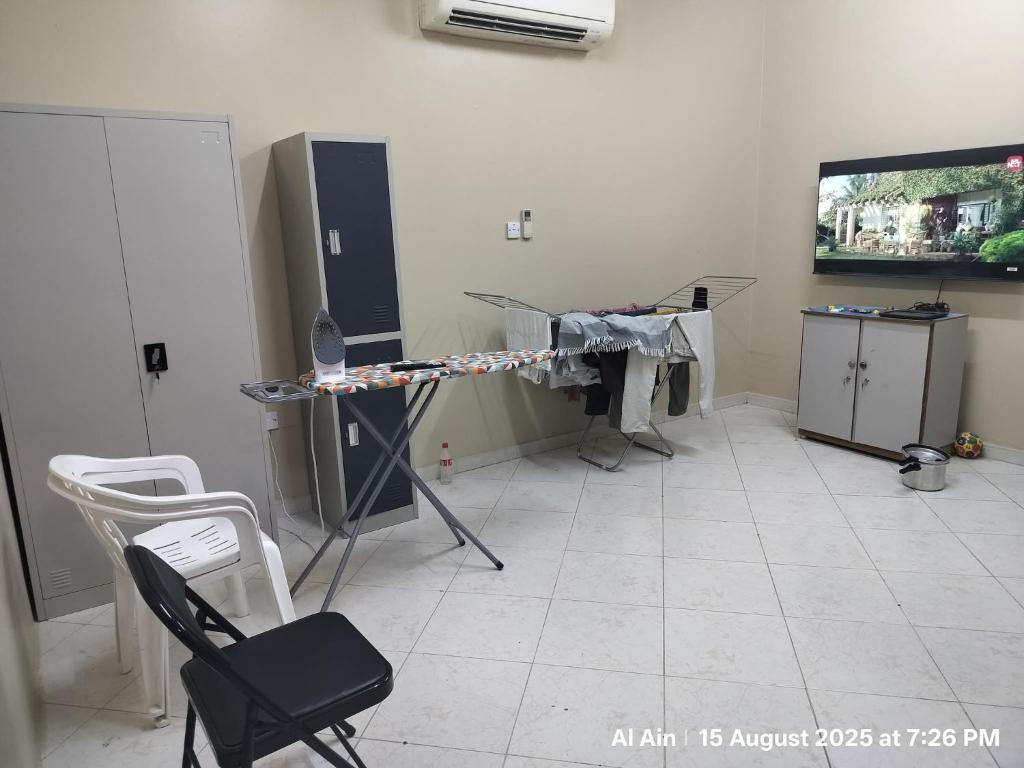 a room with a tv and a table and chairs at Happy Homes in Al Ain