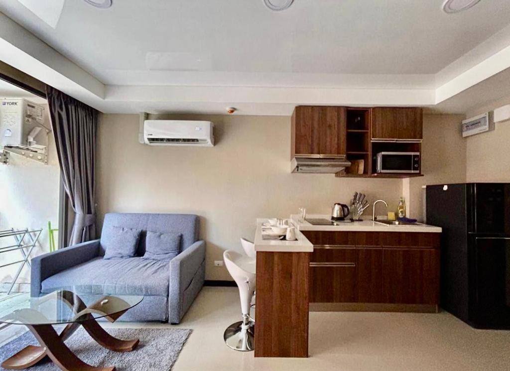 een woonkamer met een blauwe bank en een keuken bij Bright Sun Apartment with Pools in Rawai Beach