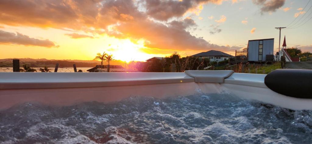 een hot tub met zonsondergang op de achtergrond bij Country Harbourside Escape in Whakapirau