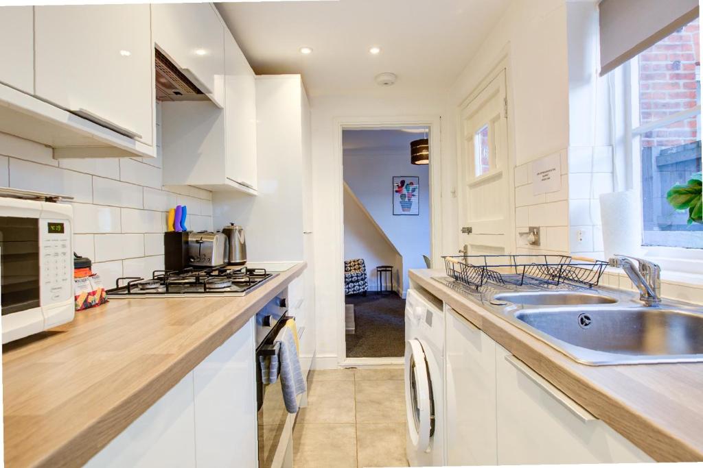 una cucina bianca con lavello e fornello di Colchester CntrCosyOfficePatioTrainParkPet a Colchester