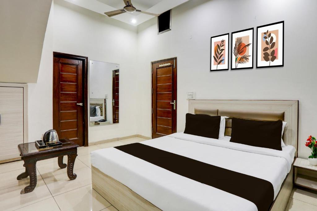a bedroom with a large bed and a table at Hotel O Lohgarh Road Zirakpur Formerly JB Plaza in Zirakpur