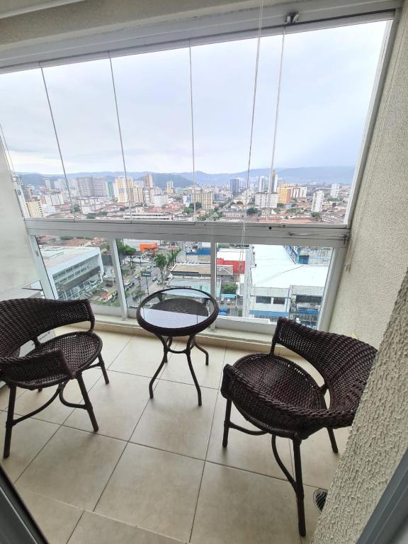 a room with a table and chairs and a large window at Apartamento Moderno 1 Quarto em Santos, Próximo à Praia e Comércio in Santos