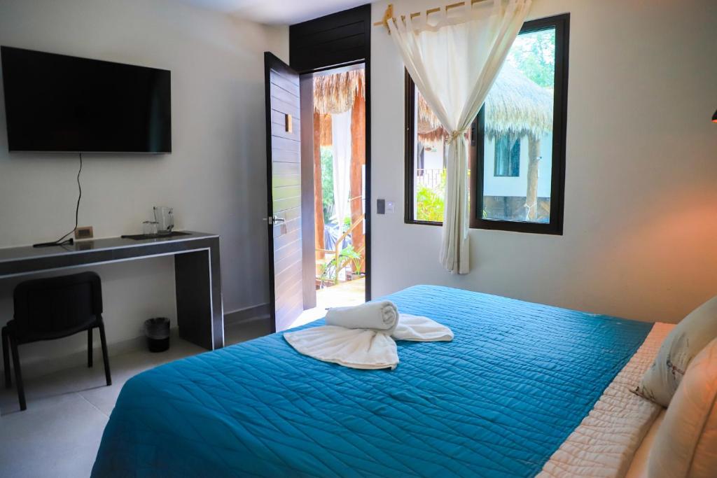 een slaapkamer met een blauw bed, een bureau en een raam bij Hotel Diosa del Agua Bacalar in Bacalar