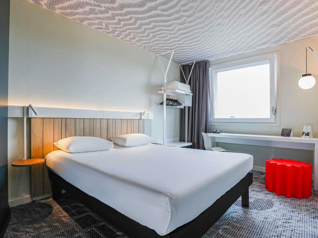 a bedroom with a large white bed and a window at Ibis Luxembourg Airport in Luxembourg