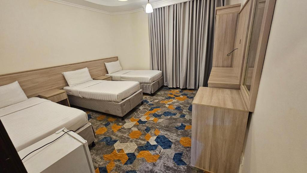 una piccola stanza con due letti e una sedia di فندق ربوة الصفوة ريع بخش a Ajyad