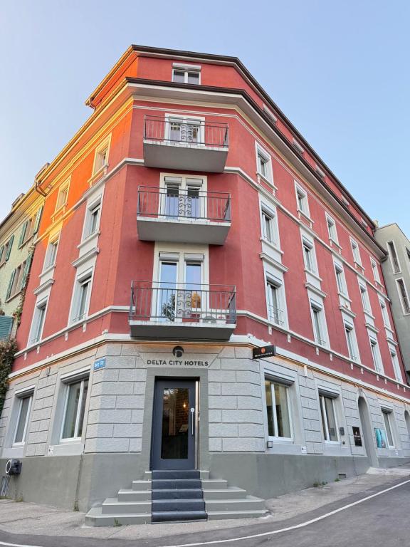 Un gran edificio rojo con dos balcones en una calle. en Delta City Hotels - Self check-in, en Zúrich